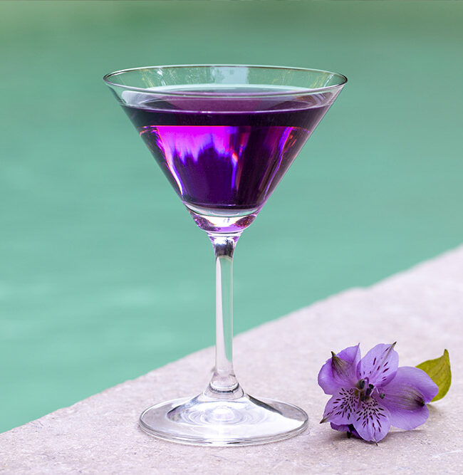 Photo d'un verre à cocktail posé sur le bord d'une piscine