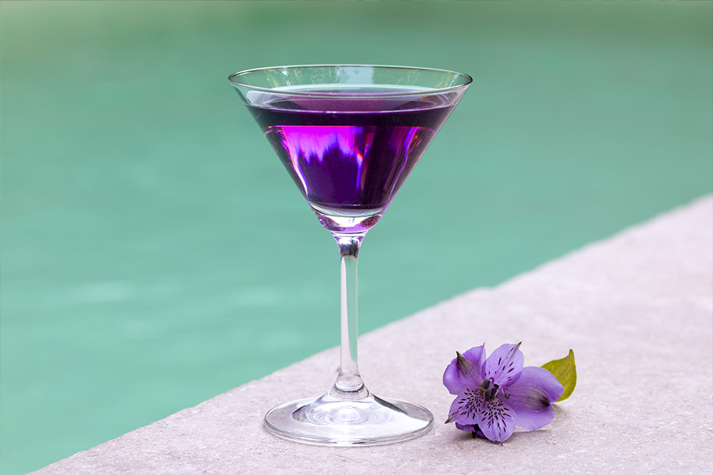 Photo d'un verre à cocktail posé sur le bord d'une piscine
